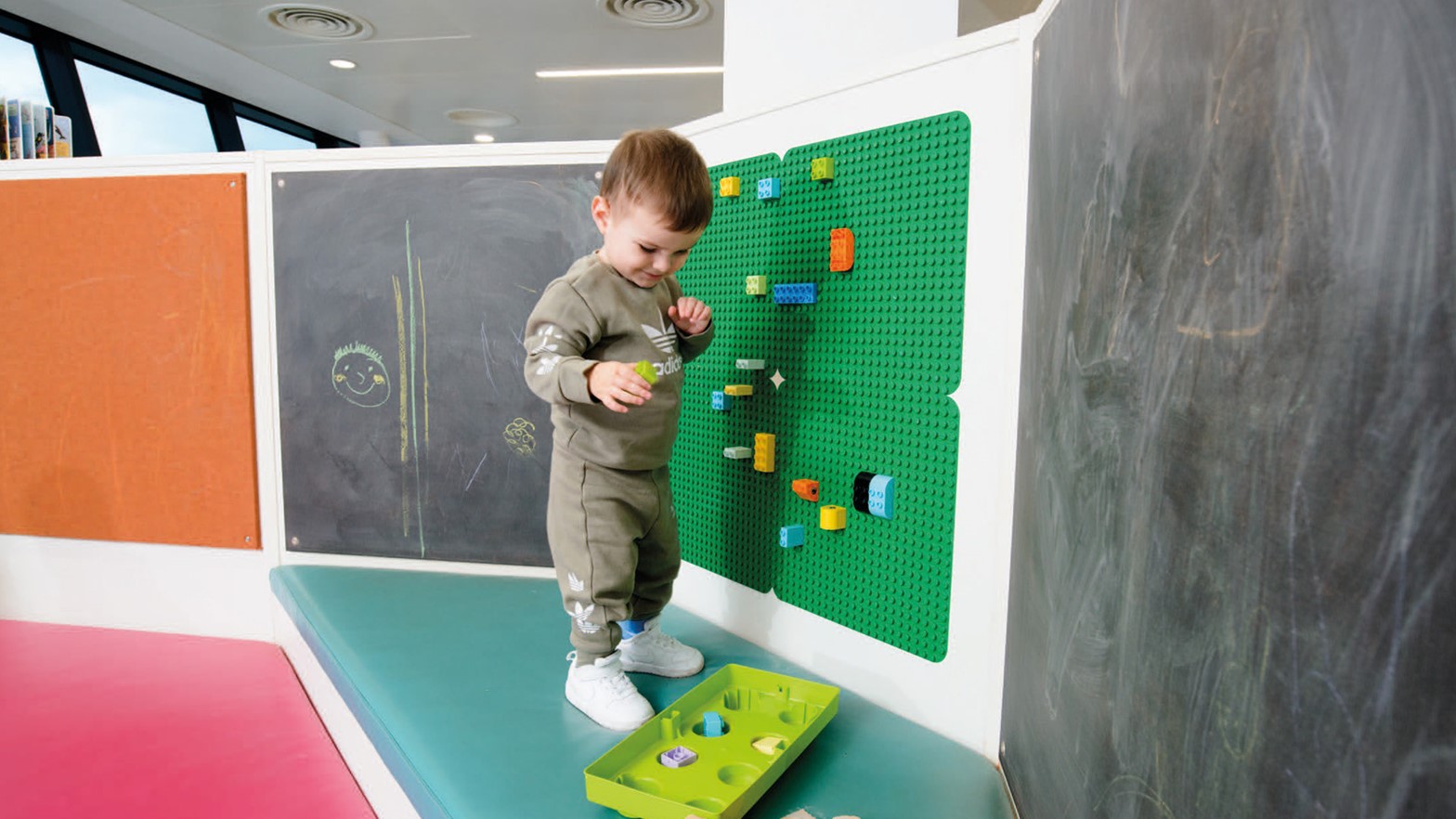 Boy putting building bricks on green board in Pontypridd Library