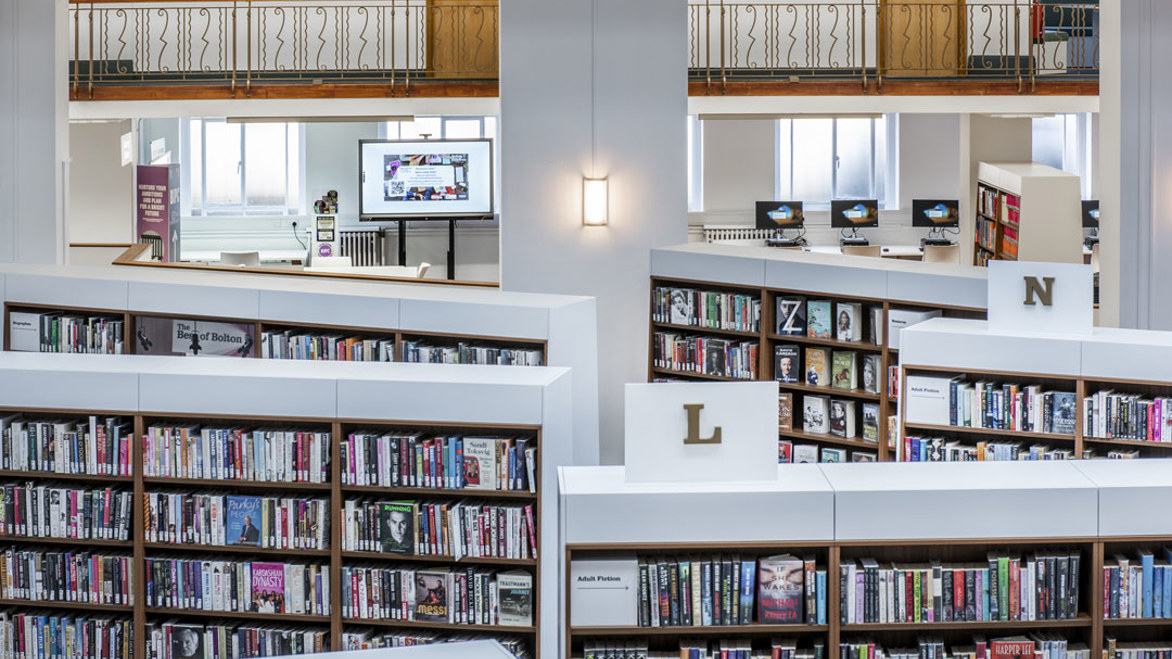 View from the second floor of Bolton Library of the new bright white alphabetically arranged bookshelves