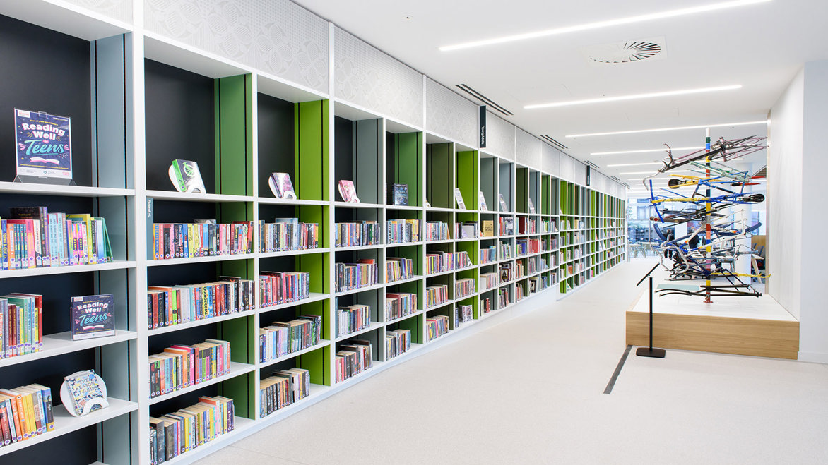 A long line of bookshelves and sculpture inside Nottingham Central Library