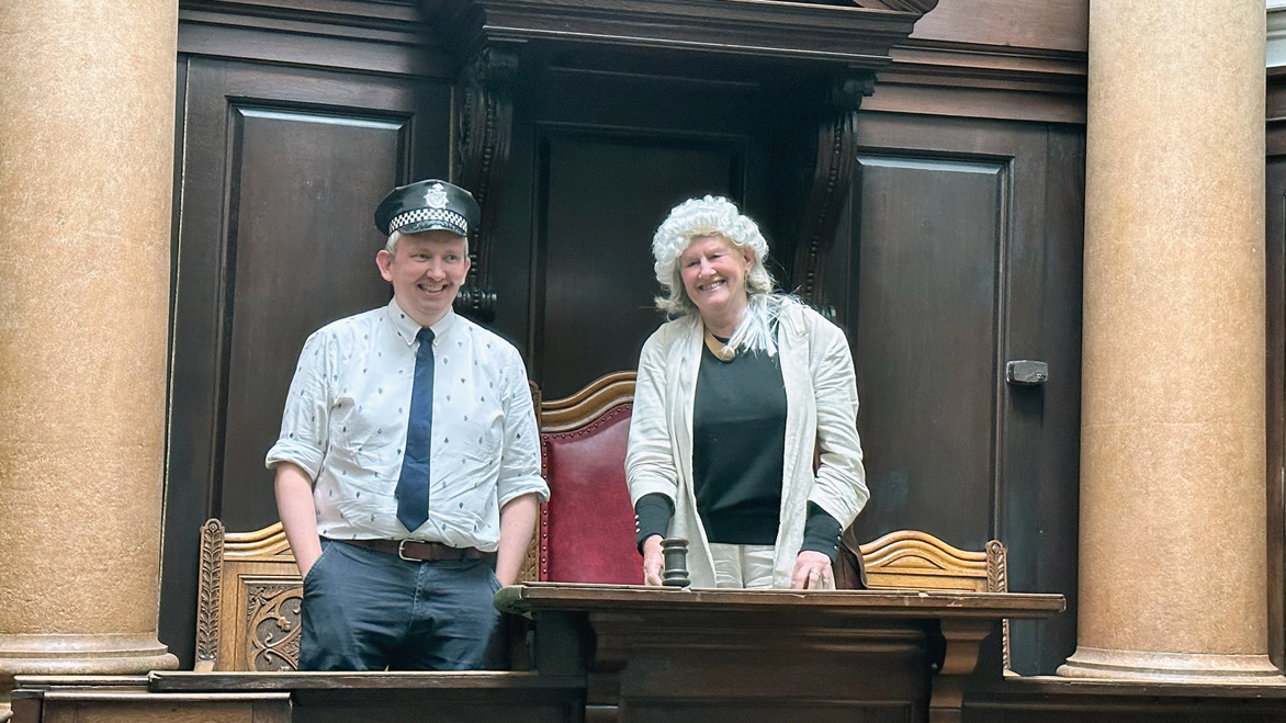 Arts Council England's Luke Burton and Designing Libraries Chief Adviser Karen Latimer role-playing in one of the old disused courts in Old Shire Hall as policeman and judge