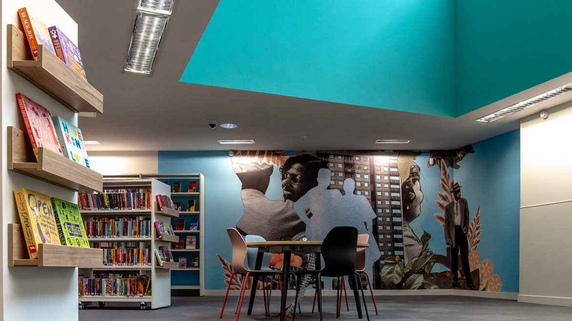 Community mural inside the library next to tables and chairs