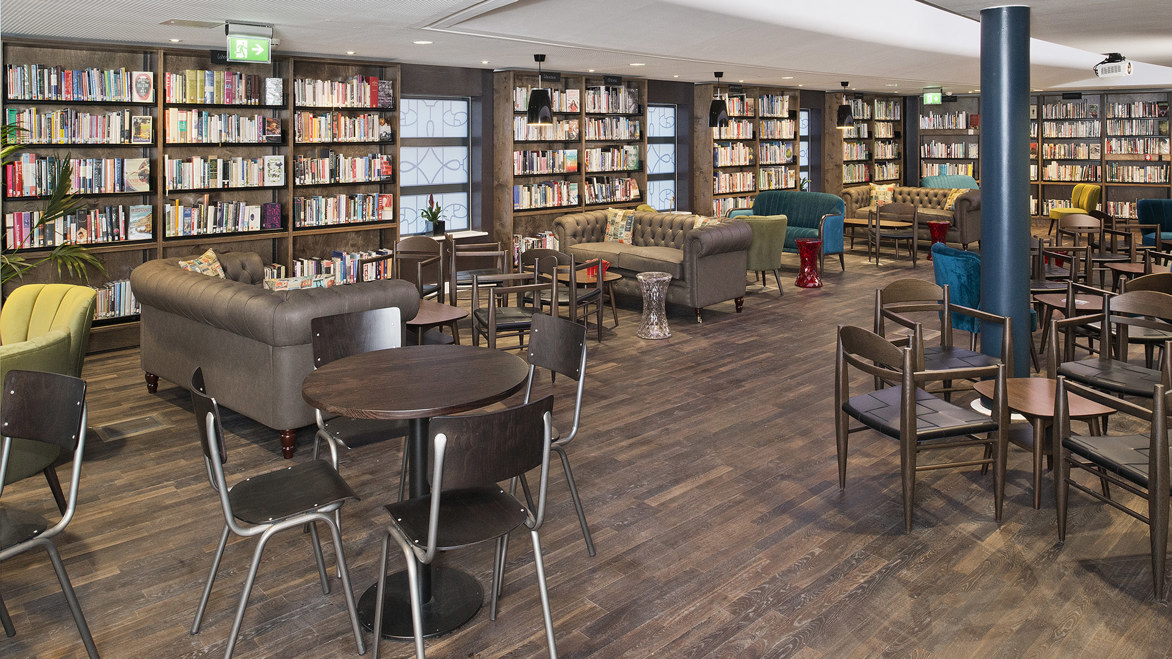 Library community area with comfortable brown sofas and bookshelves behind them