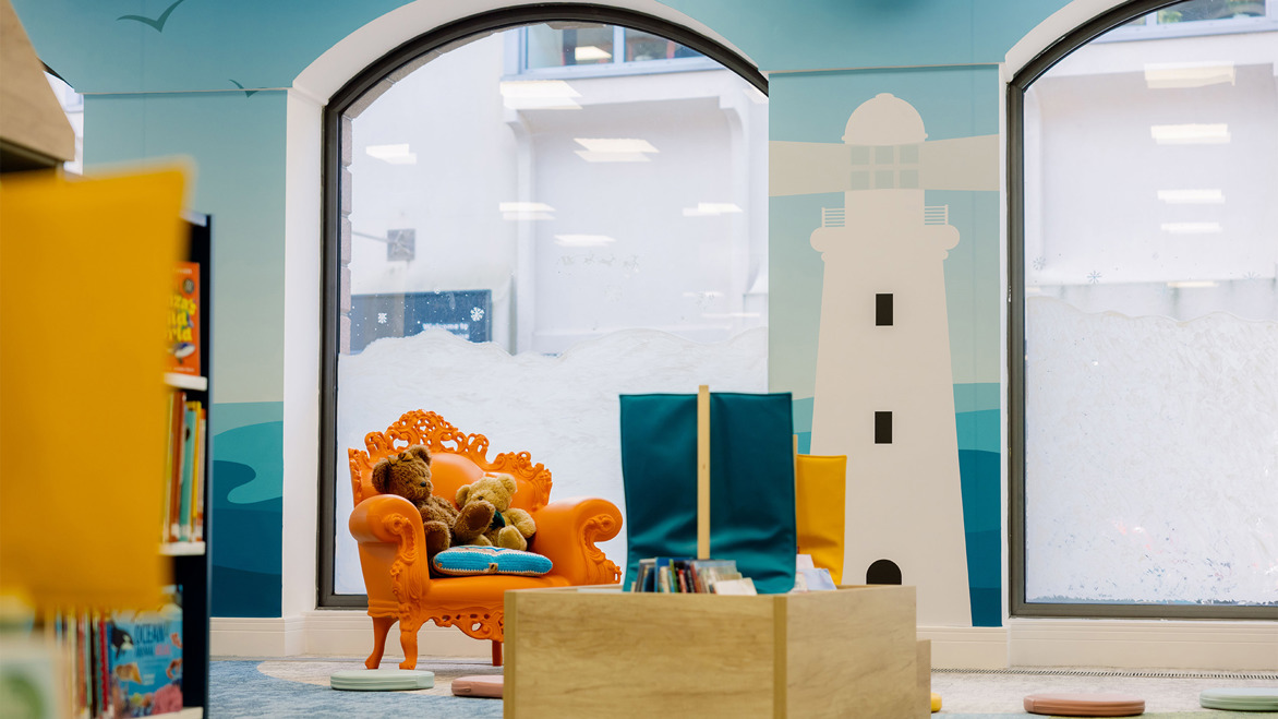 St Helier Children's Library orange chair in front of curved windows and a white painted lighthouse on the wall