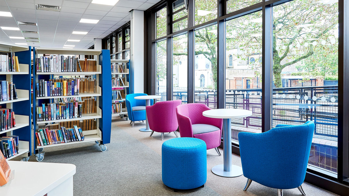 Worthing library shelving area with tables and chairs