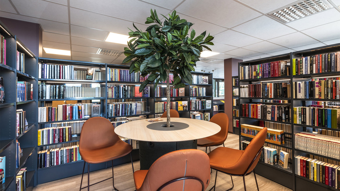 Skiptvet Public Library interior reading area table with thin tree running through the centre of it