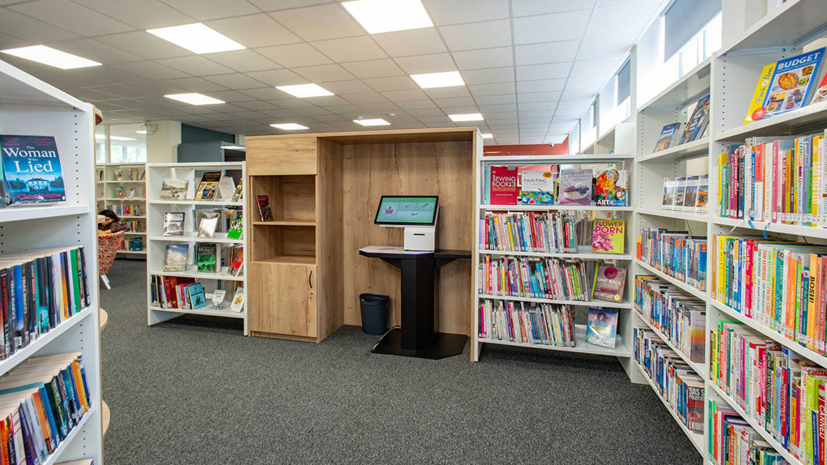 Bookshelves and computer monitor in a wooden alcove in St Pauls Cray Library, Bromley