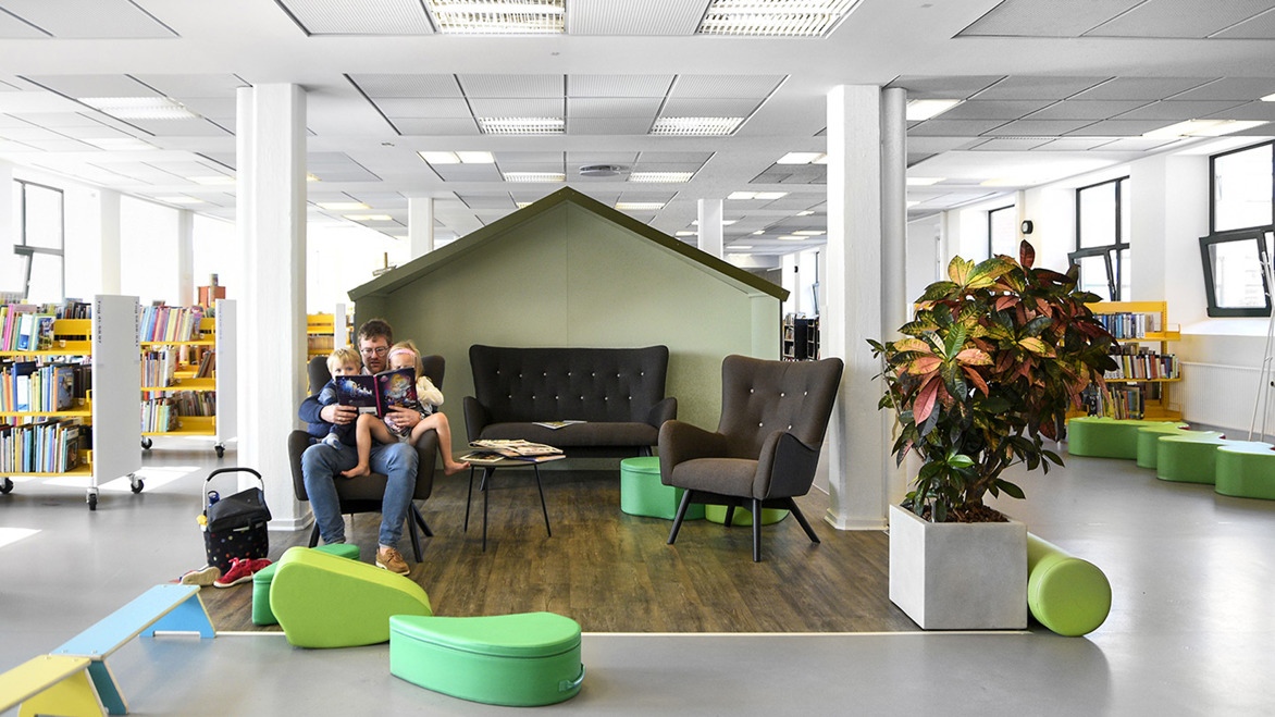 Interior design of library with small house reading alcove and man reading to children