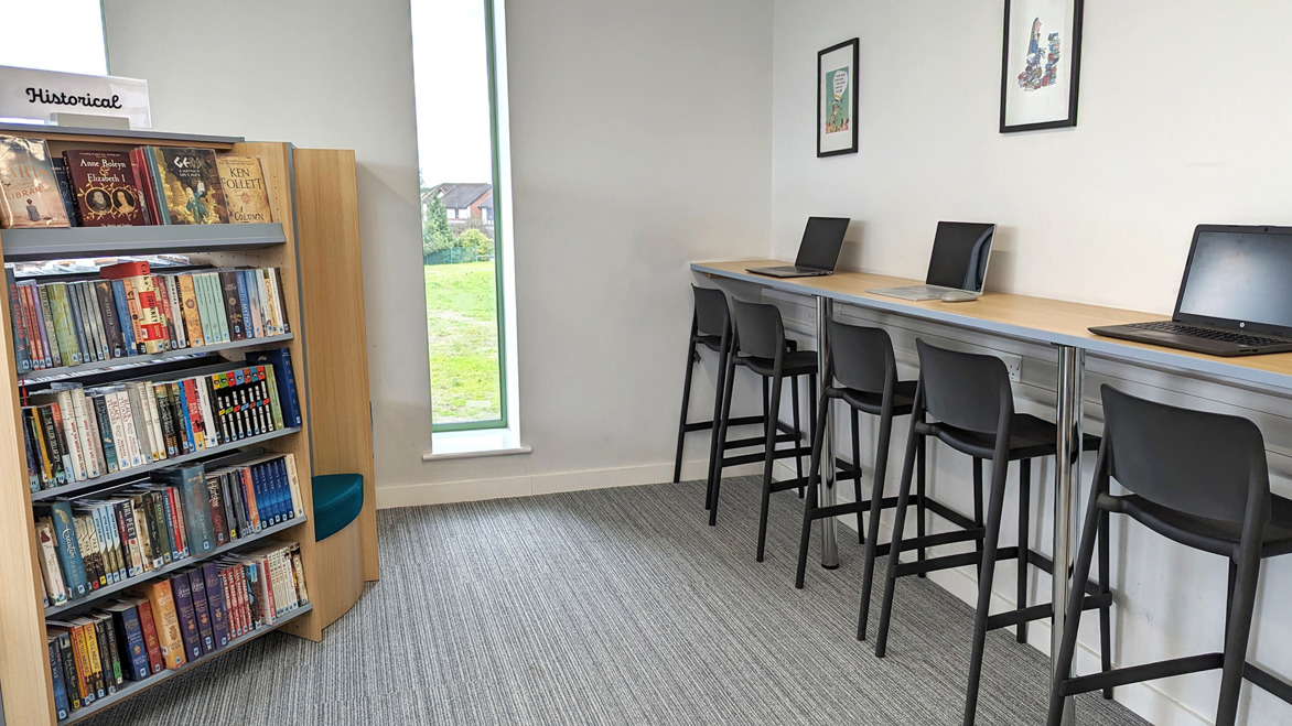 Bar height desks, stool sand bookcase in secondary school library